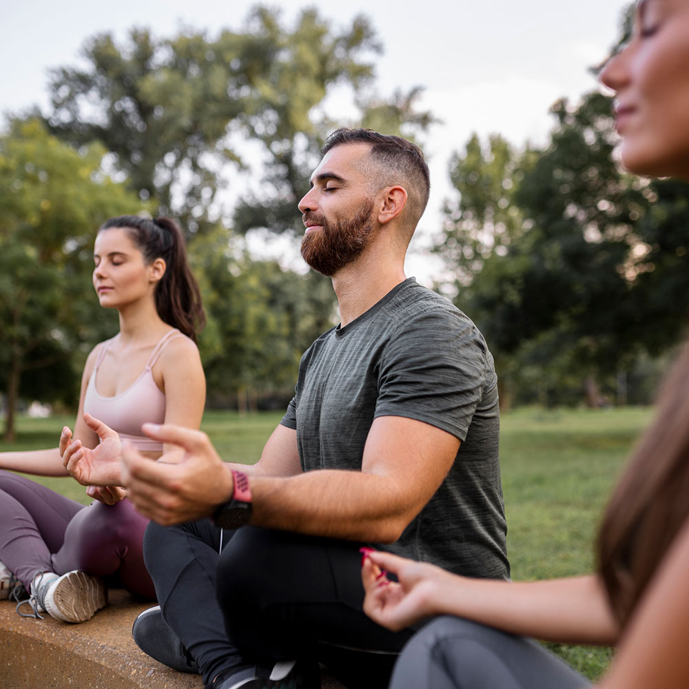 Three people meditating outdoors