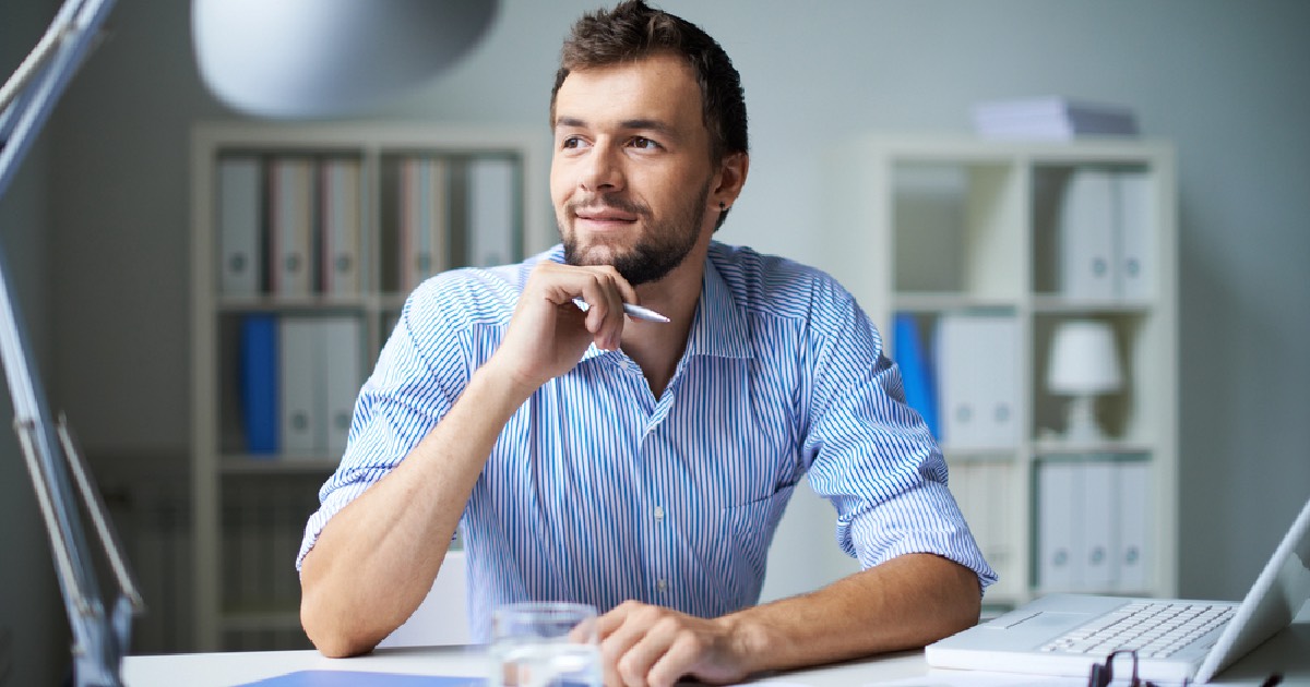 Man sitting at desk thinking positively